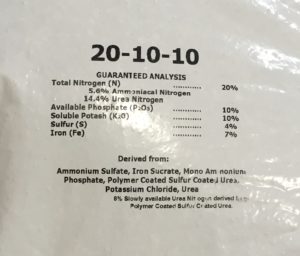 A label on a bag of fertilizer. The label reads as follows: 20-10-10 Guaranteed Analysis Total Nitrogen (N) ... 20% 5.6% Ammoniacal Nitrogen 14.4% Urea Nitrogen Available Phosphate (P2O5) ... 10% Soluble Potash (K2O) ... 10% Sulfur (S) ... 4% Iron (Fe) ... 7% Derived from: Ammonium Sulfate, Iron Sucrate, Mono Ammonium Phosphate, Polymer Coated Sulfur Coated Urea, Potassium Chloride, Urea 8% slowly available Urea Nitrogen derived from Polymer Coated Sulfur Coated Urea.