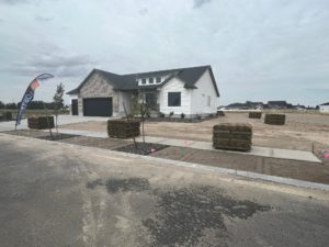 A new house with a bare yard ready for sod. Several pallets of sod are scattered on the property.