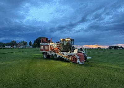 A heavy machine used to harvest the sod in the middle of a grassy field.